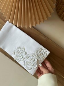 Off-white fabric envelope hand-stitched with pearls